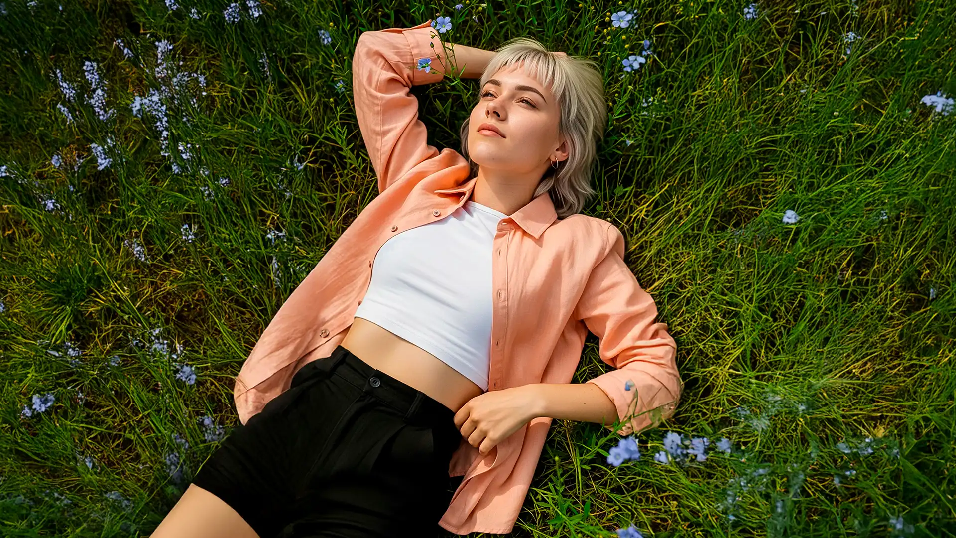 Model çimenler üzerinde turuncu gömlek ile uzanıyor – AI Video Prodüksiyon, doğallık ve yaşam tarzı temalı sahneler.